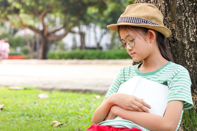 Midsection of girl wearing hat sitting in park