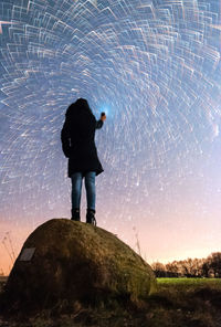 Rear view of man standing on rock against sky