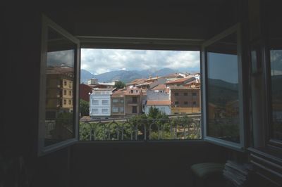 Houses against sky seen through window