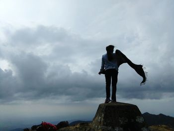 Rear view of man standing on rock against sky