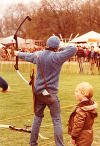 Rear view of two men playing on grassland