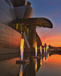 Statue by water against sky during sunset