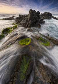 Scenic view of rocks in sea against sky