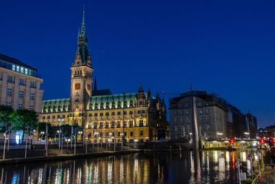 Illuminated buildings against blue sky at night