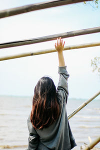 Rear view of woman standing by railing against sky