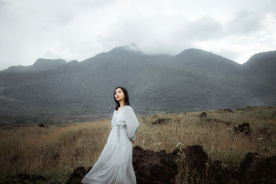 Young woman standing on mountain against sky