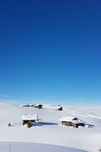 Houses on snow covered landscape against blue sky