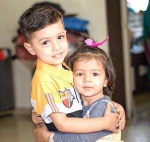 Portrait of boy embracing sister at home