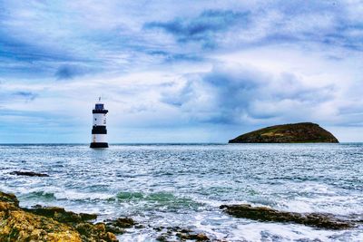 Lighthouse by sea against sky