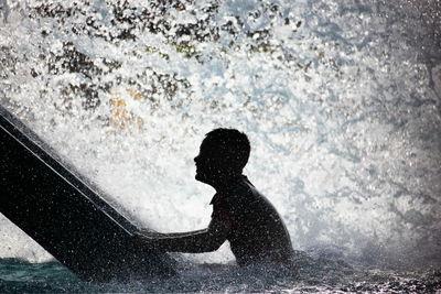 Side view of man sitting in water