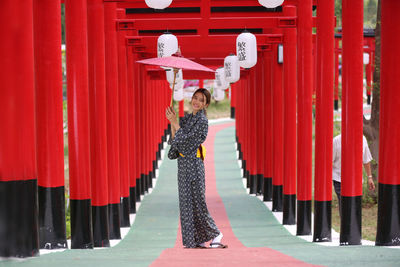 Portrait of a smiling woman standing against red wall