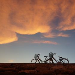 Bicycles parked on field against sky during sunset