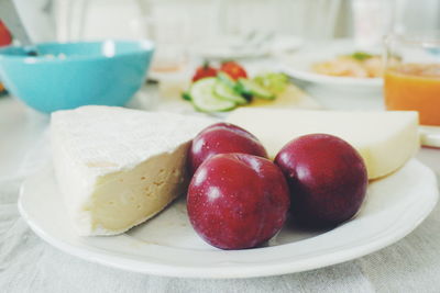 Plums and cheese served in plate on table