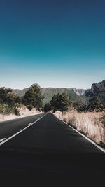 Empty road against clear blue sky