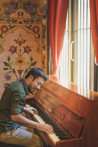 Smiling man playing piano at home