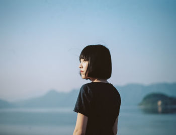 Woman standing at seaside against clear sky