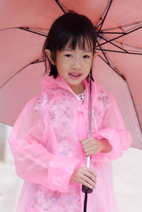 Close-up portrait of smiling cute girl wearing pink raincoat