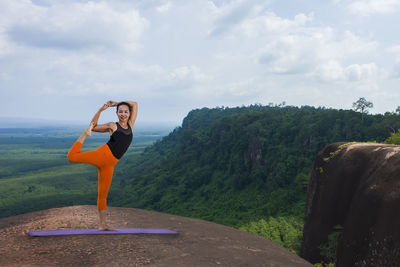 Woman with arms raised against sky