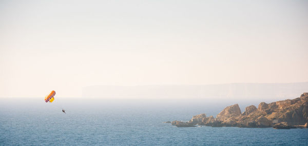 People parasailing over sea against clear sky