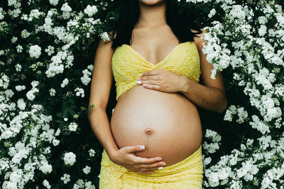 Midsection of woman touching flower