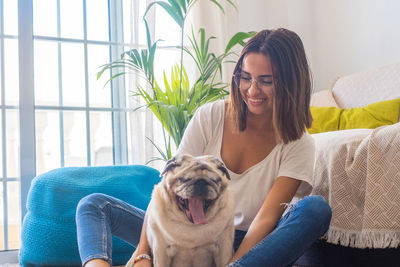 Portrait of young woman with dog at home