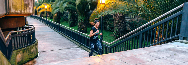 Female runner training up stairs over in urban runway on sunset