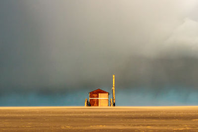 Tower on land by sea against sky