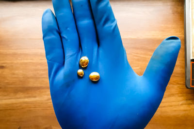 Close-up of hand holding blue wooden table