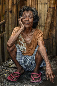 Portrait of homeless senior woman against wooden wall