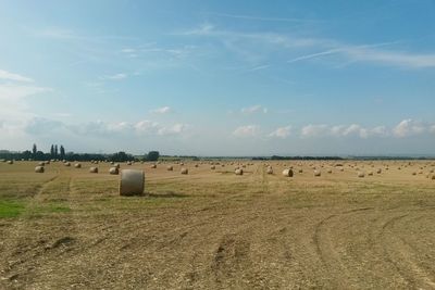 Hay bales on field against sky