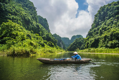 Man in boat on lake against sky