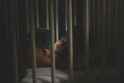 Portrait of boy using smart phone while lying in crib