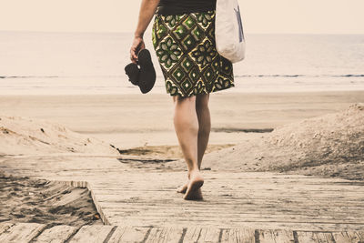 Low section of woman walking at beach