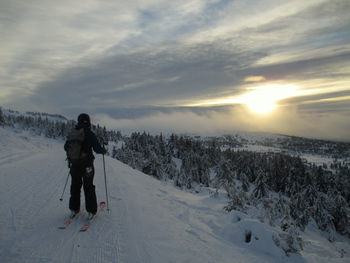 Rear view of man skiing on snow covered landscape