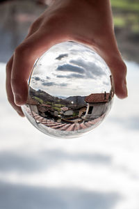 Close-up of person holding crystal glass against sky