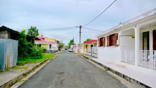 Empty road amidst buildings in city against sky