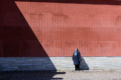 Rear view of man standing against brick wall
