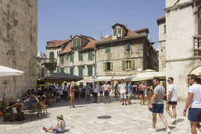 Group of people walking against buildings in city