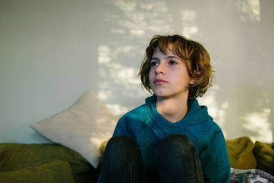 Girl sits on couch in dappled window light