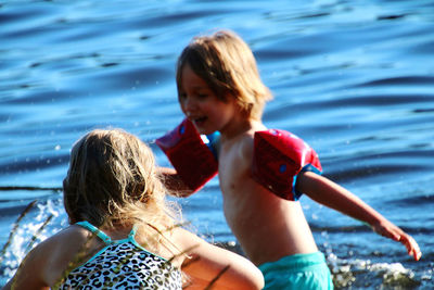 Girl and boy going swimming with sea in background