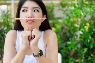 Close-up of playful young woman balancing pencil on lips