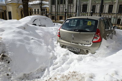 Cars on snow covered buildings in city