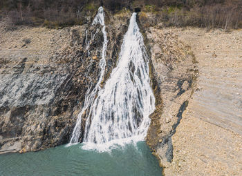 Panoramic drone shot of a waterfall flowing into lac chambon in french alps