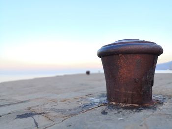 Close-up of rusty metal on beach against clear sky