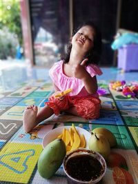 Portrait of girl having food while sitting on floor