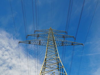 Low angle view of electricity pylon against blue sky