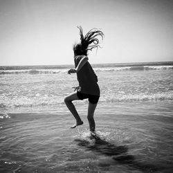 Full length of woman dancing on beach against clear sky