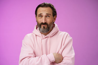 Portrait of man standing against pink background