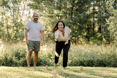 Smiling woman with male partner playing molkky in yard