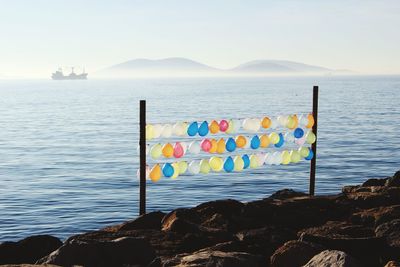 Balloons on rocky coastline against sky at kartal